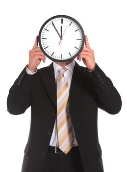 A businessman holding a clock that shows the eleventh hour right in front of his face. All on white background.