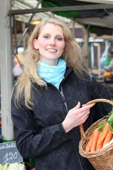 Woman buys vegetables in the market with a basket.