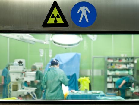 Warning signs on door of operative room with busy doctors