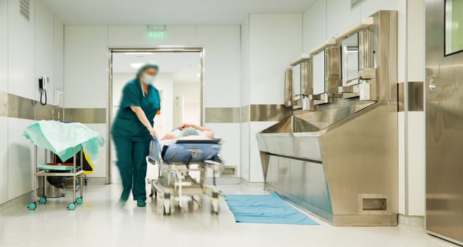 Blurred figures of nurse running with patient on trolley entering surgery