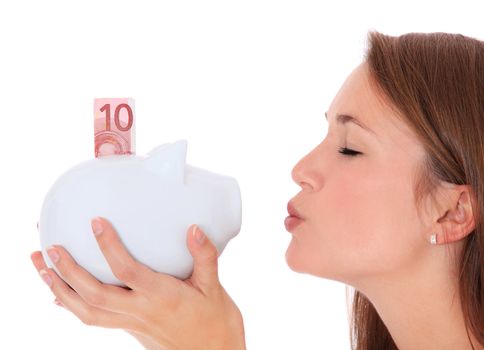 Attractive young woman kissing piggy bank. All on white background.