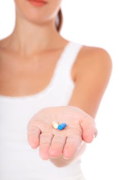 Attractive young woman holding pills. All on white background.