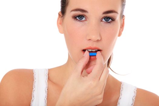 Attractive young woman taking a pill. All on white background.