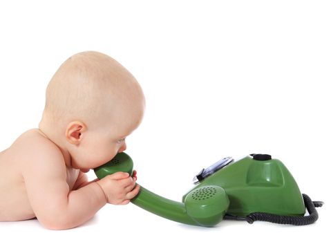 Newborn child playing with a green telephone. All isolated on white background.