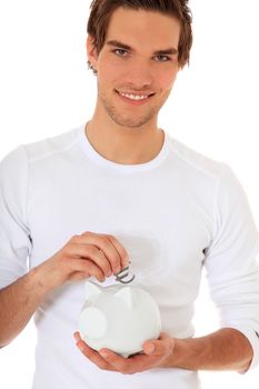 Attractive young man puts Euro symbol in piggy bank. All on white background.