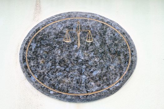 blank and Empty Mable Plate with Golden Scale of justice on White Wall at Street