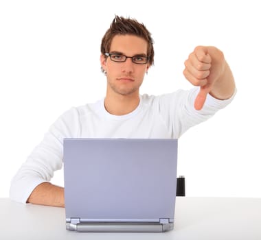 Young guy showing thumbs down while using notebook computer. All on white background.