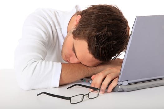 Young guy falls asleep on his notebook computer. All on white background.