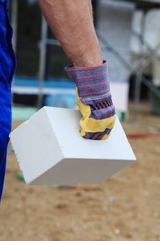 Manual worker on construction site carrying a brick.