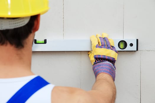 Construction worker using level.