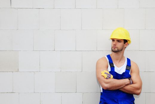 Manual worker on construction site standing infront of a white wall.