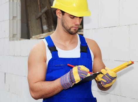 Manual worker on construction site writing on clipboard.