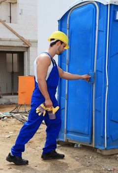 Manual worker on construction site using the toilet.