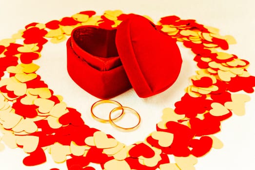 Two rings in front of a red heart shaped box