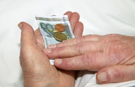 Old wrinkled hands of an elderly person, counting money.