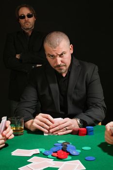 Photo of a very serious poker player staring across the table. Cards have been altered to be generic.