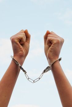 Handcuffed woman's hands against blue sky