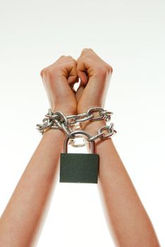 Woman's hands tied up with chains against light background