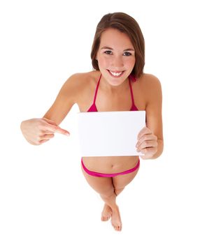 Attractive young woman in bikini pointing at blank white sign. All on white background.