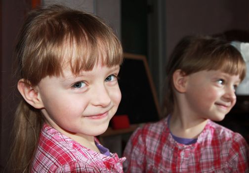 Smiling pretty little girl with mirror reflection. Close up