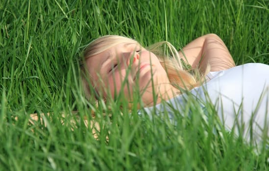 Attractive young woman resting outside on green meadow.