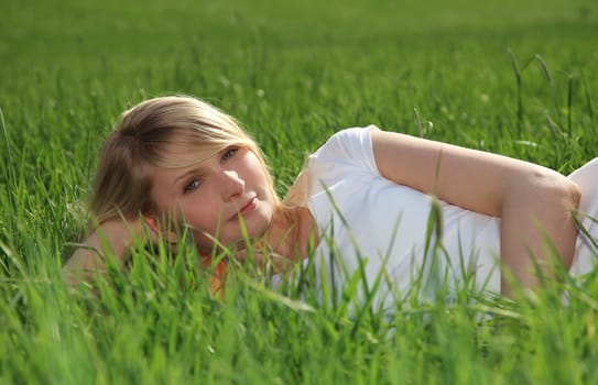 Attractive young woman resting outside on green meadow.