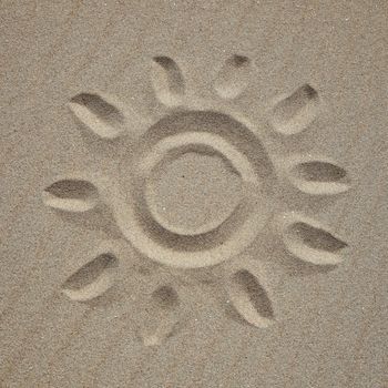 A sun drawn in the sand at the beach.