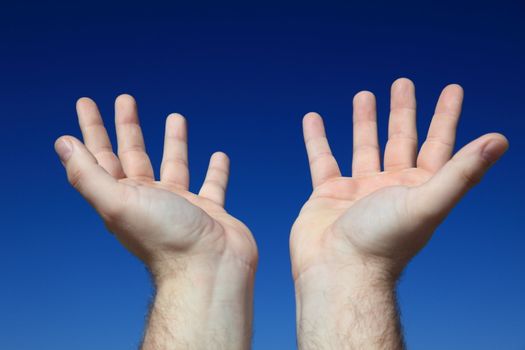 A persons hands praying to the sky.