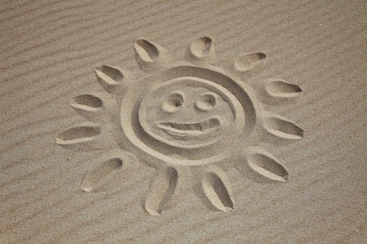 A sun drawn in the sand at the beach .