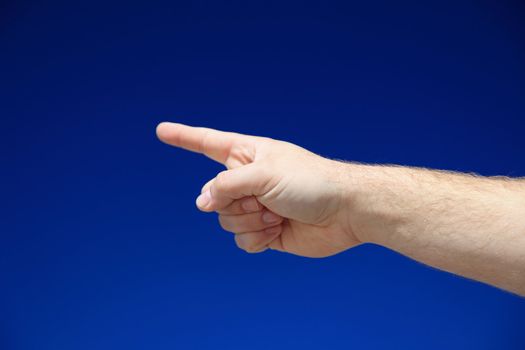 A person pointing with finger in front of bright blue sky.