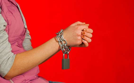 Hands tied up with chains against red background