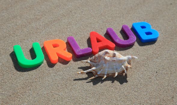 The German term urlaub (Engl.: holiday) written in colorful letters on the sand.