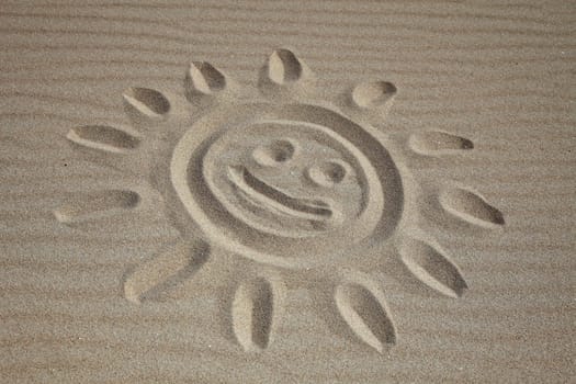 A sun drawn in the sand at the beach