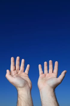 A persons hands praying to the sky.