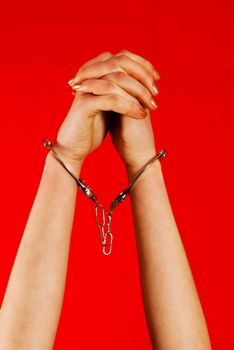 Handcuffed woman's hands against red background