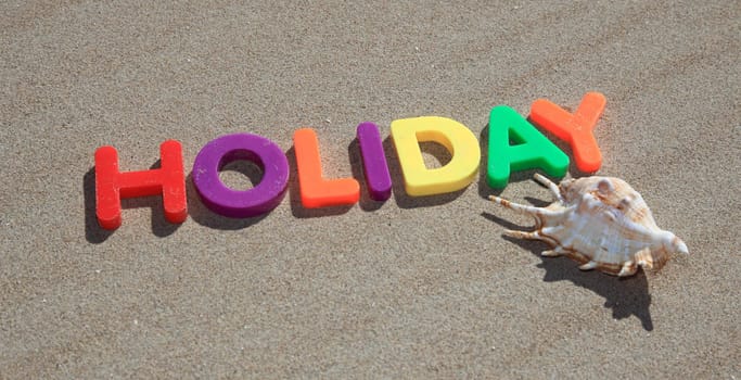 The term holiday written in colorful letters on the sand.