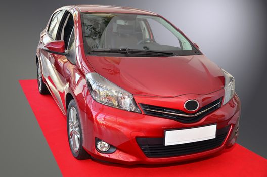 Small Toyota Yaris, model 2012. Standing on red carpet.