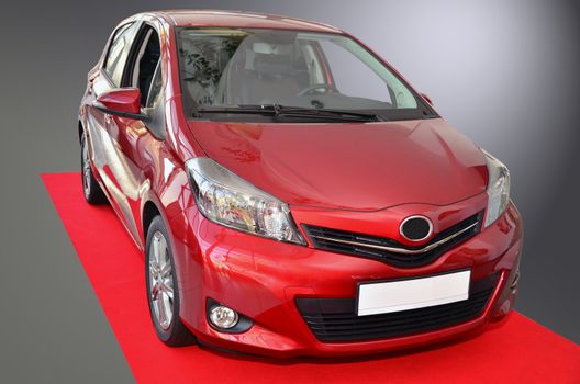 Small Toyota Yaris, model 2012. Standing on red carpet.