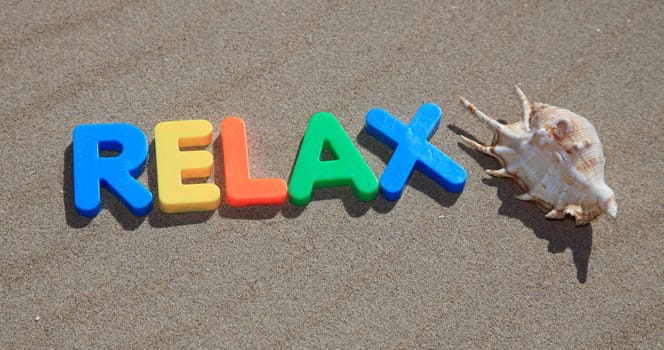 The term relax written in colorful letters on the sand.