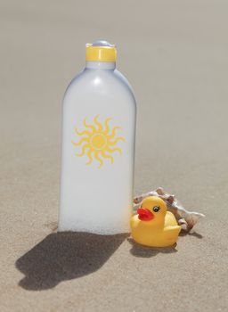 A bottle with suntan lotion standing in the sand.