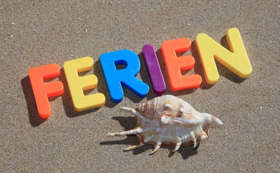 The german term ferien written in colorful letters on the sand.