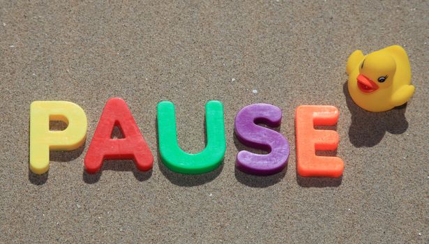 The term pause in colorful letters on sand.