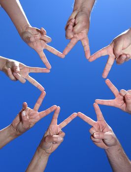 Various peoples hands in front of bright blue sky forming a star.