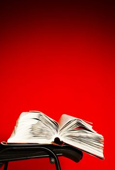 Open book laying on the chair against red background