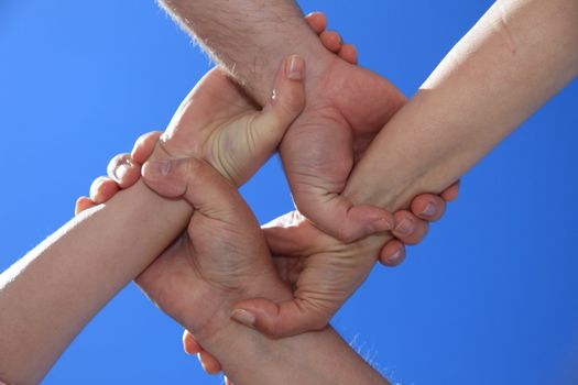 Various peoples hands in front of bright blue sky.