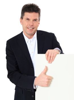 Attractive middle-aged man making thumbs up sign next to a white board. All on white background.