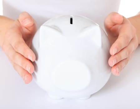 Human hands holding piggy bank. All on white background. Selective focus on piggy bank in foreground.