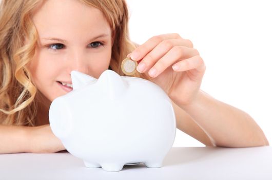 Attractive girl puts money in her piggy bank. All on white background.