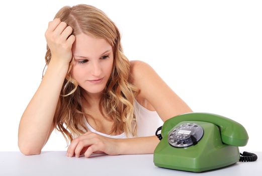 Attractive young woman awaits a phone call. All on white background.