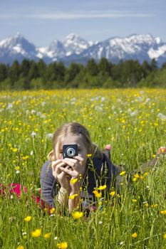 young girl taking photos by digital camera in the mountains